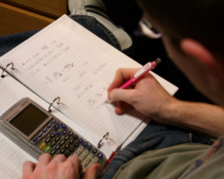 Adolescent qui fait ses devoirs de mathématiques avec calculatrice et cahier